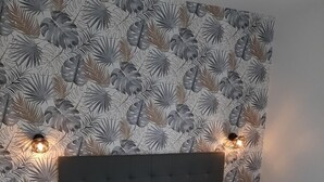 Un dormitorio con una cama, dos mesitas de noche y una pared decorada con un diseño de hojas.