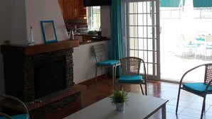 Amplia sala de estar con chimenea, una mesa de comedor y una cocina al fondo.