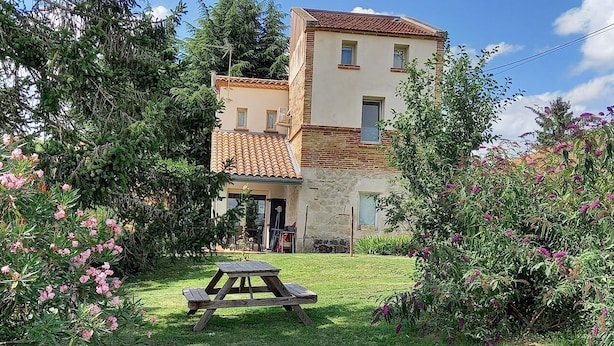 Une maison à deux étages avec une table de patio dans le jardin avant.