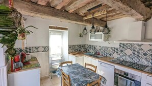 Une cuisine avec un plafond en bois, des carreaux décoratifs, une table à manger et un four à micro-ondes.