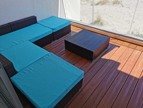 A balcony with wicker furniture and a view of the beach.