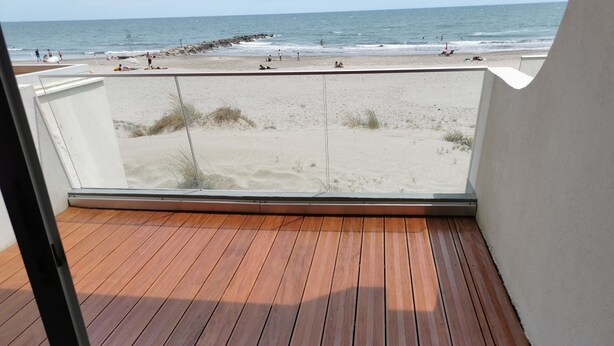 A wooden deck with a view of the beach and ocean. - Apartment F3 1st line Carnon East, feet in the water (Mauguio)