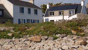 Un bâtiment situé sur la côte, doté d’une façade en pierre, d’un toit en pente et d’un petit balcon.