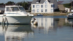 Un bateau était amarré dans un port tranquille, avec une maison qui se dessinait à l’arrière-plan.