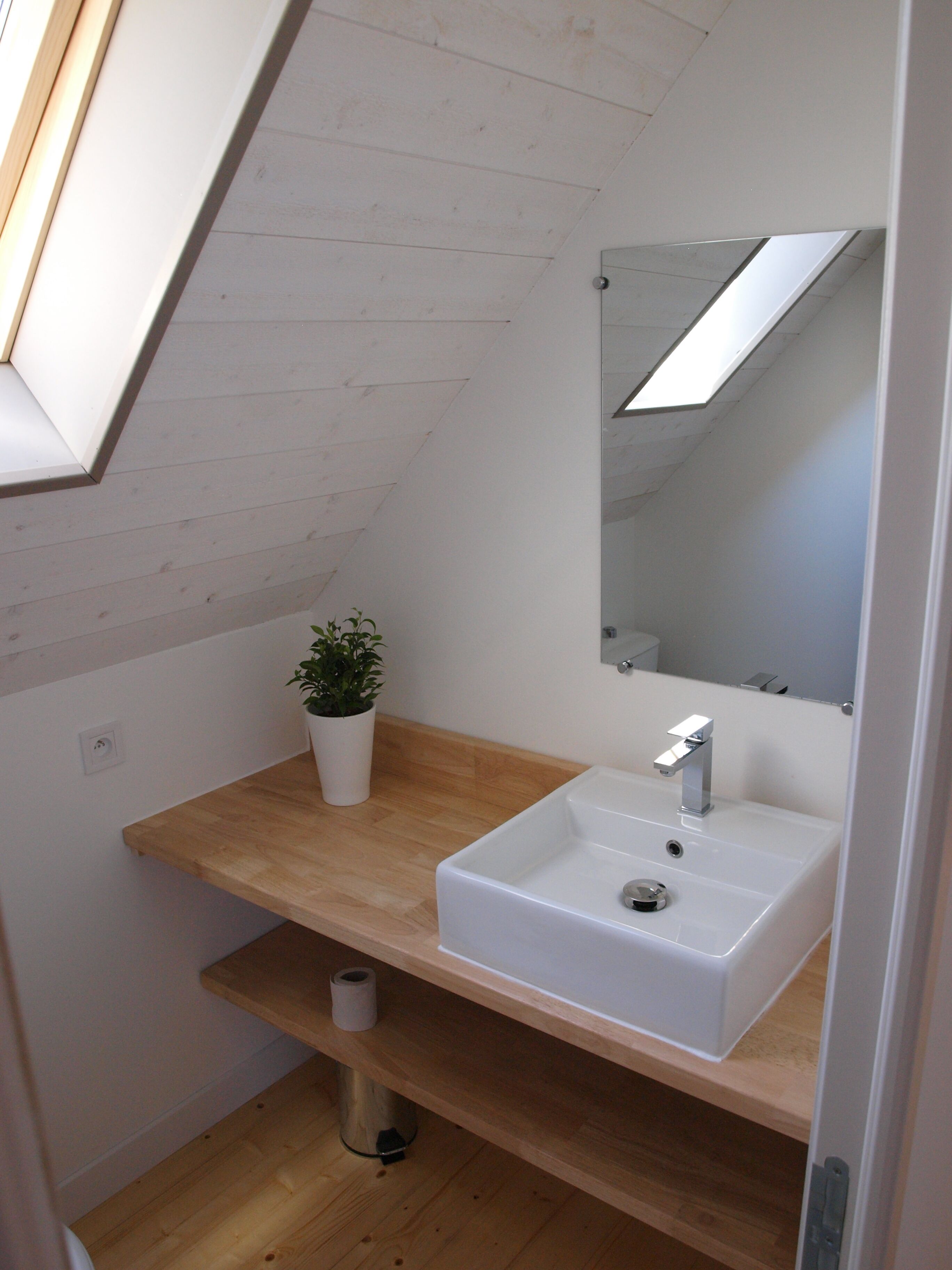Une salle de bain moderne avec un lavabo blanc, un miroir et une étagère en bois.