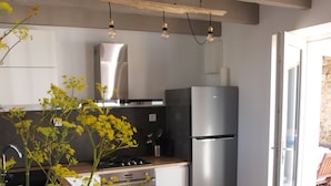Une cuisine moderne équipée d’un réfrigérateur en acier inoxydable, d’une cuisinière et d’un évier. On y trouve un plan de travail en bois et un vase rempli de fleurs jaunes.
