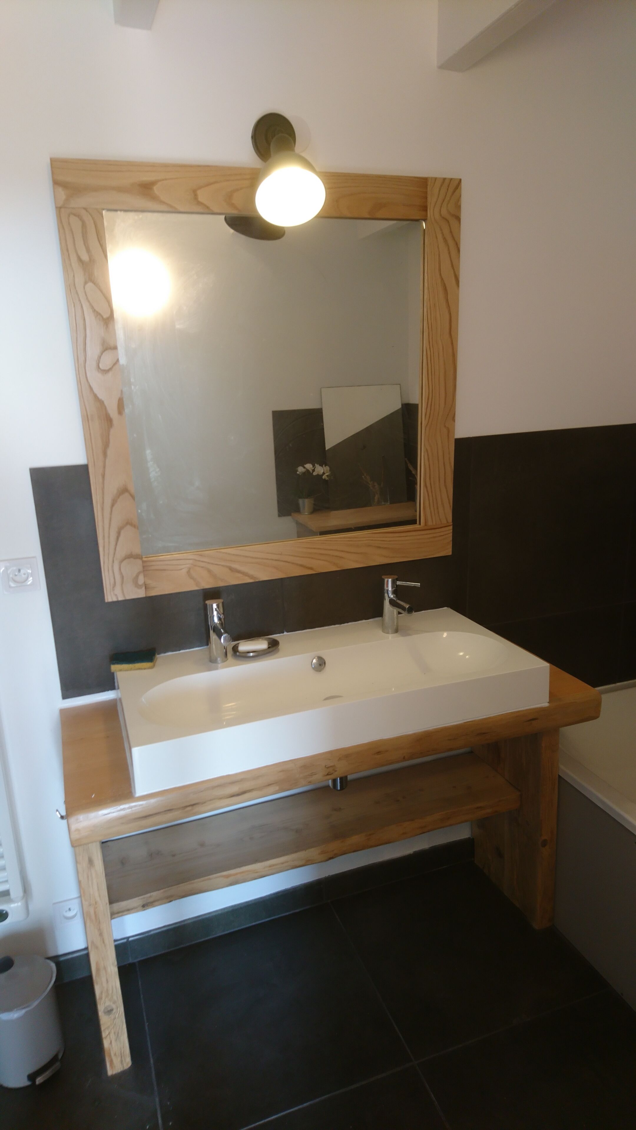 A bathroom with a wooden vanity, a white sink, and a mirror with a wooden frame.