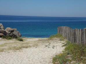 A sandy beach with a wooden fence and rocks. - The sea for garden, home to four feet in water (Penmarch)