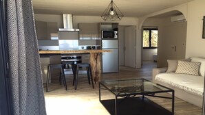 A modern kitchen with a central island, bar stools, and a glass coffee table. - T4 feet in water  (Ghisonaccia)