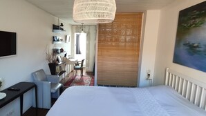 Une chambre à coucher avec un lit, un bureau, une chaise, un téléviseur et un tableau.