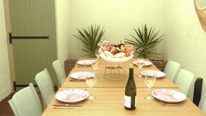 Une table à manger dressée avec des assiettes, des verres à vin et une bouteille de vin, entourée de chaises.