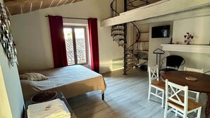 Een slaapkamer met een bed, een bureau en een wenteltrap.