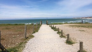 Un chemin de gravier menant à la plage, bordé de poteaux en bois de chaque côté.