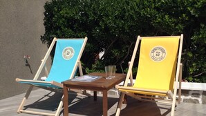 Deux chaises de plage, séparées par une petite table, et portant toutes deux un logo et une inscription indiquant « Espace Vert Volant ».