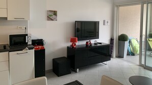 Una cocina moderna con microondas, tostadora y armario negro. Un televisor de pantalla plana está montado en la pared sobre un mueble de entretenimiento negro.