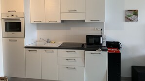 Una cocina moderna con armarios blancos, horno integrado, microondas y pileta.