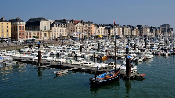 Een jachthaven vol boten afgemeerd aan steigers, omringd door historische gebouwen.