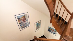 Een houten trap met een leuning en een witte muur met ingelijste foto's.