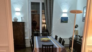 Een eethoek met een tafel gedekt voor twee personen, een leren bank en een tafelkleed met een patroon.