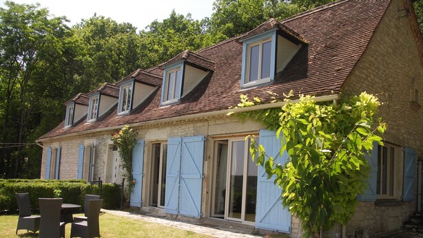 A stone building with a tiled roof, multiple windows, and a small garden area with outdoor furniture. - Country house, quiet location, private pool. Country house. Magnificent view. (Montcuq en Quercy Blanc)