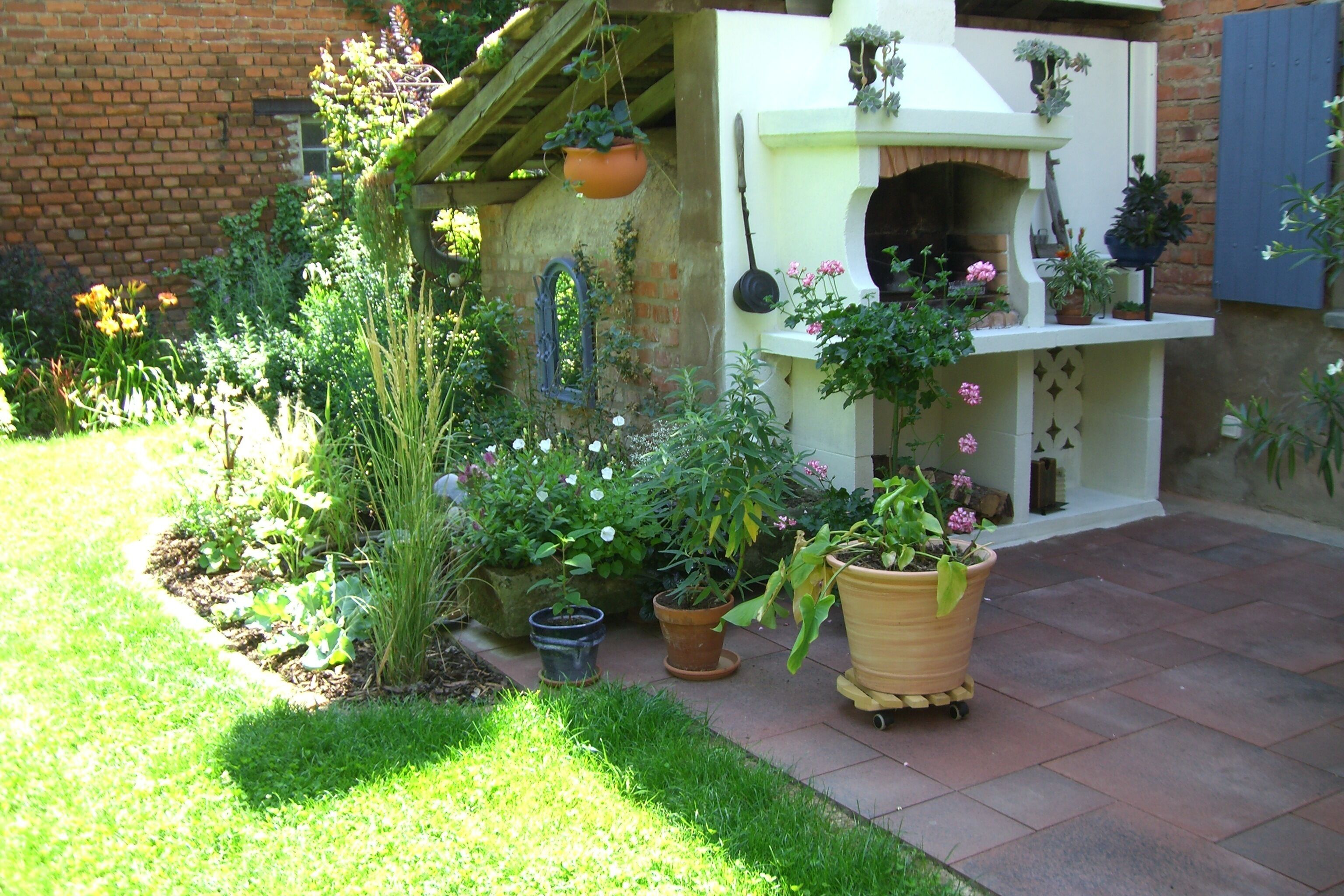 Un jardin agrémenté de différentes plantes en pot et doté d’un mur en briques.
