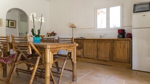 Una cucina con mobili in legno, un tavolo da pranzo con sedie e un frigorifero.