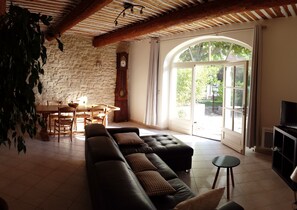 Un salon avec un mur en pierre, des meubles en bois, une grande fenêtre et un téléviseur.