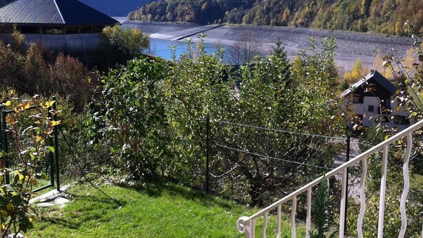 A mountainous landscape with a river, a building with a dark roof, and a staircase leading down. - Vaujany, alpes d'huez, ski, bike, hike, trail chalet 40m2 2/5p, (Vaujany)