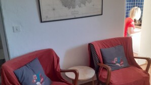 Dos sillones con tapicería roja y cojines estampados, una mesita redonda y un mapa enmarcado en la pared.