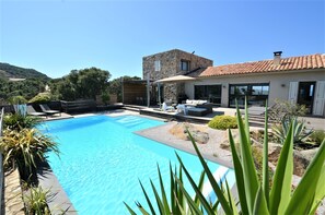 A modern house with a swimming pool, outdoor seating, and a stone facade. - CALVI, SEA VIEW, MODERN VILLA, HEATED POOL, JACUZZI,  (Calvi)