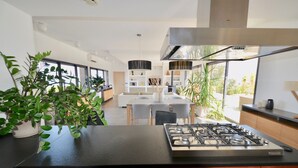 A modern kitchen with a gas stove, wooden cabinets, and a dining area with a white table and chairs.