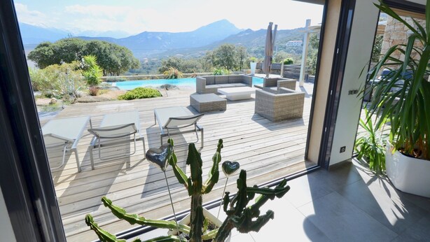 A deck with outdoor furniture, a pool, and a view of mountains.