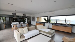 A modern living room with a sectional sofa, a dining area, and a kitchen.