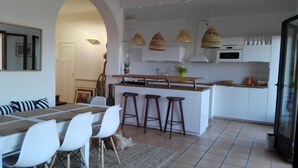 Una cocina moderna con armarios blancos, una isla de madera y tres taburetes de bar.