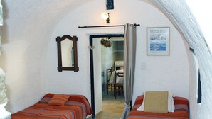 Habitació amb dos llits, un mirall, un quadre amb marc i una porta que dona a una cuina.