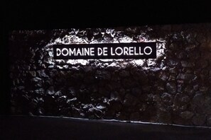 Une enseigne portant l'inscription « DOMAINE DE LORELLO » sur un mur à texture.