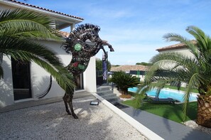 A modern house with a swimming pool, palm trees, and a unique sculpture. - NEAR PEZENAS, lovely villa, private heated pool, quiet location, shops. (Tourbes)