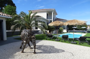 A modern villa with a swimming pool, outdoor seating, and a decorative metal sculpture. - NEAR PEZENAS, lovely villa, private heated pool, quiet location, shops. (Tourbes)