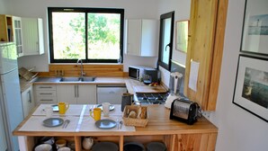 A compact kitchen with a central island, white cabinets, and a large window. - ROYAN Charming house in the pines 400 m from the beach, Parc district  (Saint-Georges-de-Didonne)