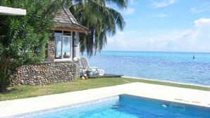 A swimming pool with a stone wall and a view of the ocean.