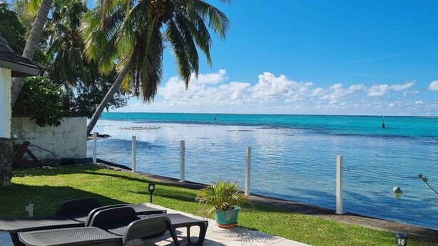 A poolside area with lounge chairs and a view of the ocean.
