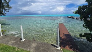 A clear view of a wooden dock extending into turquoise waters, with a concrete walkway leading to it.