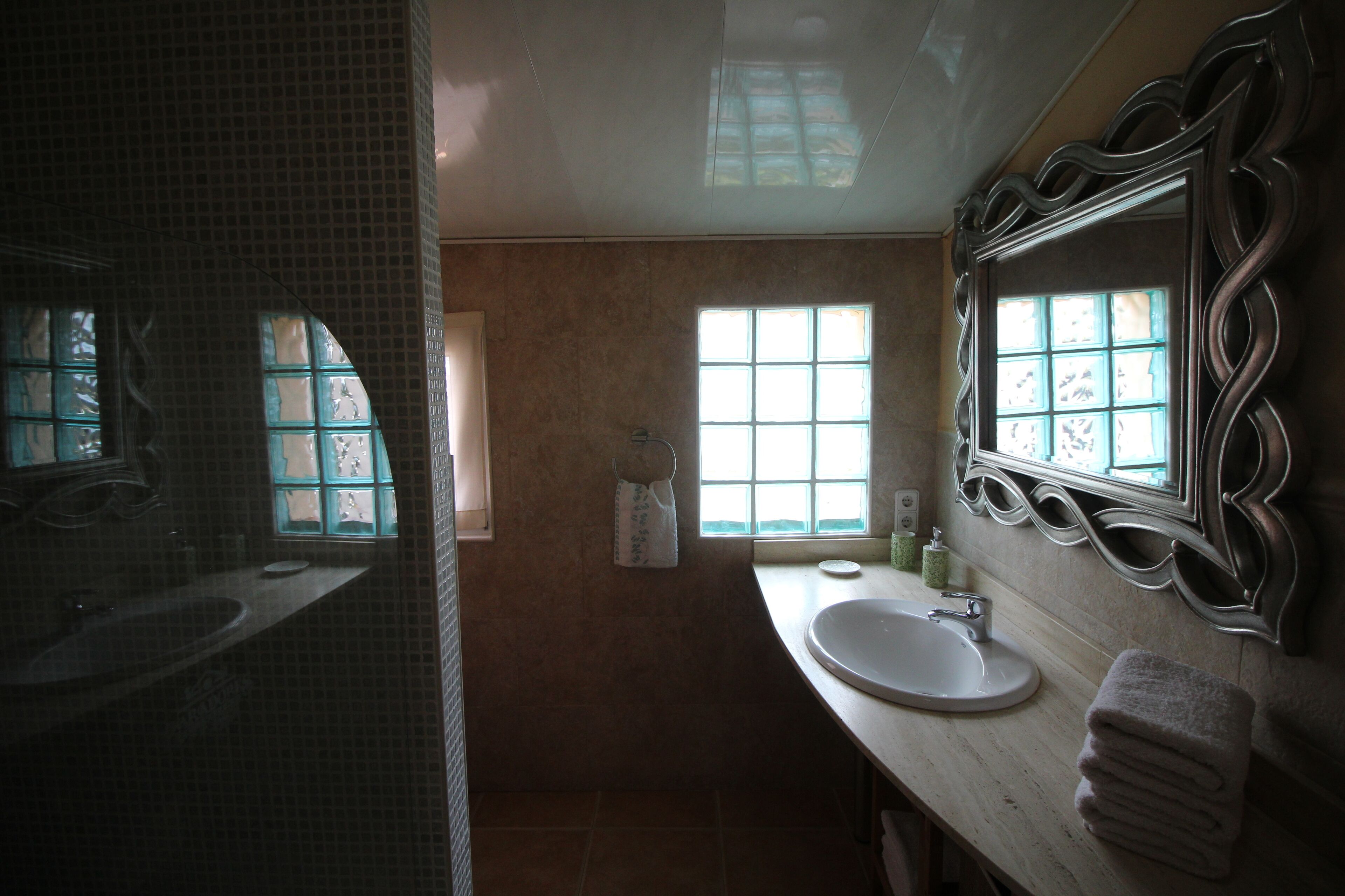 A bathroom with a large mirror, a sink, and a window.