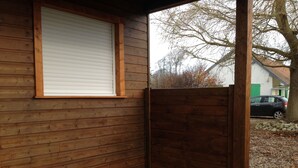 Un muro esterno in legno con una finestra e un cancello di legno chiuso.