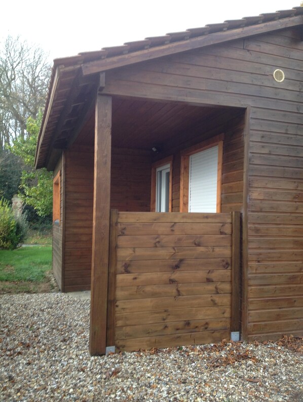 A wooden cabin with a gravel driveway and a wooden gate.