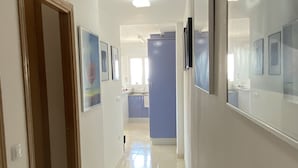 Un couloir avec une porte en bois, un mur bleu et un réfrigérateur.