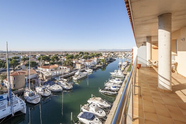 Un port de plaisance où des bateaux sont amarrés le long d’un canal, entouré de bâtiments et de verdure.