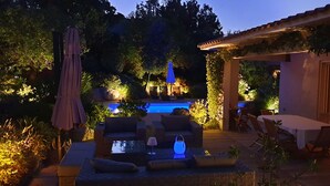 Un'area patio esterna con piscina, posti a sedere e un pergolato.