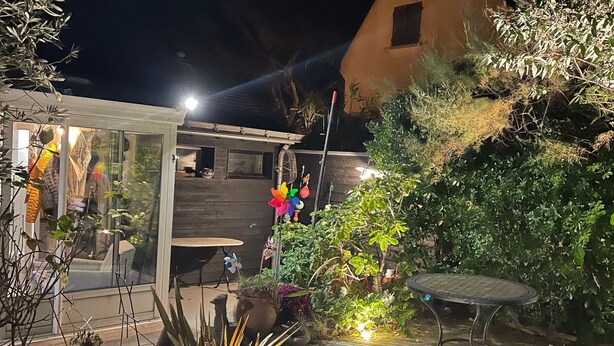 Un patio con terraza de madera, plantas en macetas y una pequeña mesa.