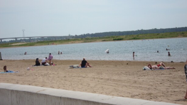 Una platja amb gent que pren el sol i nedant.